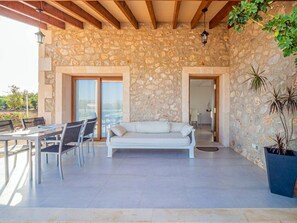 A stone-walled room with a white sofa, dining table, and chairs.