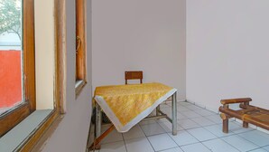 Een kamer met een raam, een stoel en een tafel met een gele tafelkleed.