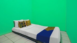 Een bed met witte lakens, twee kussens met een patroon en een blauw accent.
