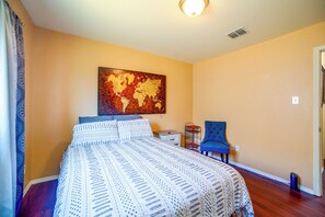 A hotel room with a bed, a chair, a nightstand, and a wall-mounted artwork. - Fenced Yard, Workspace, Garage: Ft Worth Home Base (Fort Worth)