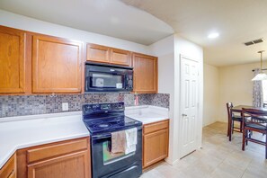 A kitchen with wooden cabinets, a black stove, and a microwave.