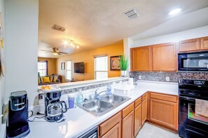 A modern kitchen with wooden cabinets, a built-in microwave, and a coffee maker on the counter. - Fenced Yard, Workspace, Garage: Ft Worth Home Base (Fort Worth)