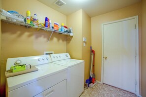 A laundry area with a washing machine, dryer, and a mop on the floor.