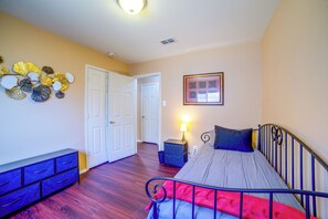 A bedroom with a bed, dresser, nightstand, lamp, and decorative wall art.