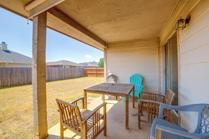 A covered patio with a table and chairs, a wooden fence, and a view of a residential area.