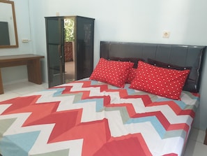 A bedroom with a bed featuring a chevron-patterned bedspread, a dark headboard, and two red pillows with white heart patterns. - Capital O 92612 Penginapan D'alas Purwo & BeachNearPadang Savana Sadengan (Banyuwangi)
