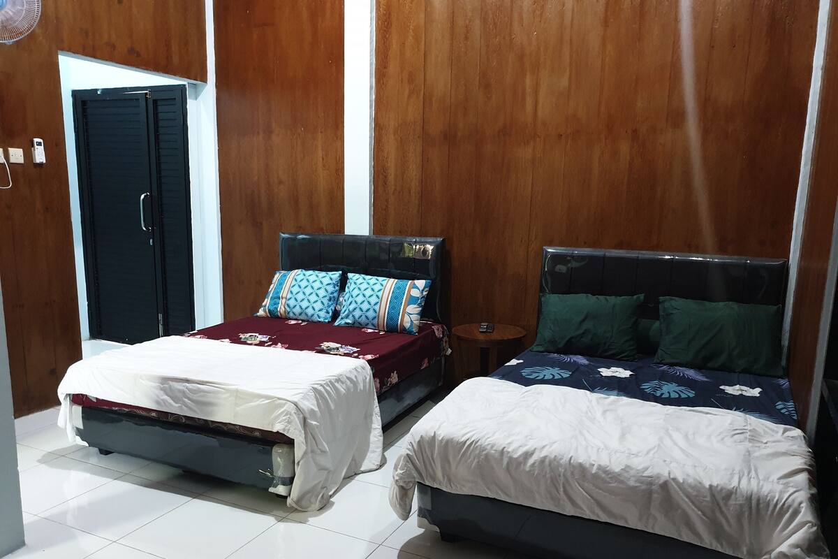 Ein Hotelzimmer mit zwei Betten, einem Holzschrank und einem kleinen runden Tisch.