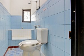 A bathroom with blue tiled walls, a white toilet, and a white bathtub. - Hotel O Mw 46 Guesthouse (Yogyakarta)