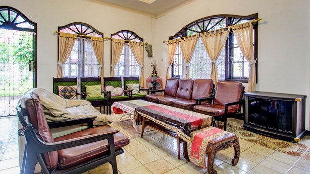 A spacious living room with a sofa set, a television, and a decorative table. - Hotel O Mw 46 Guesthouse (Yogyakarta)