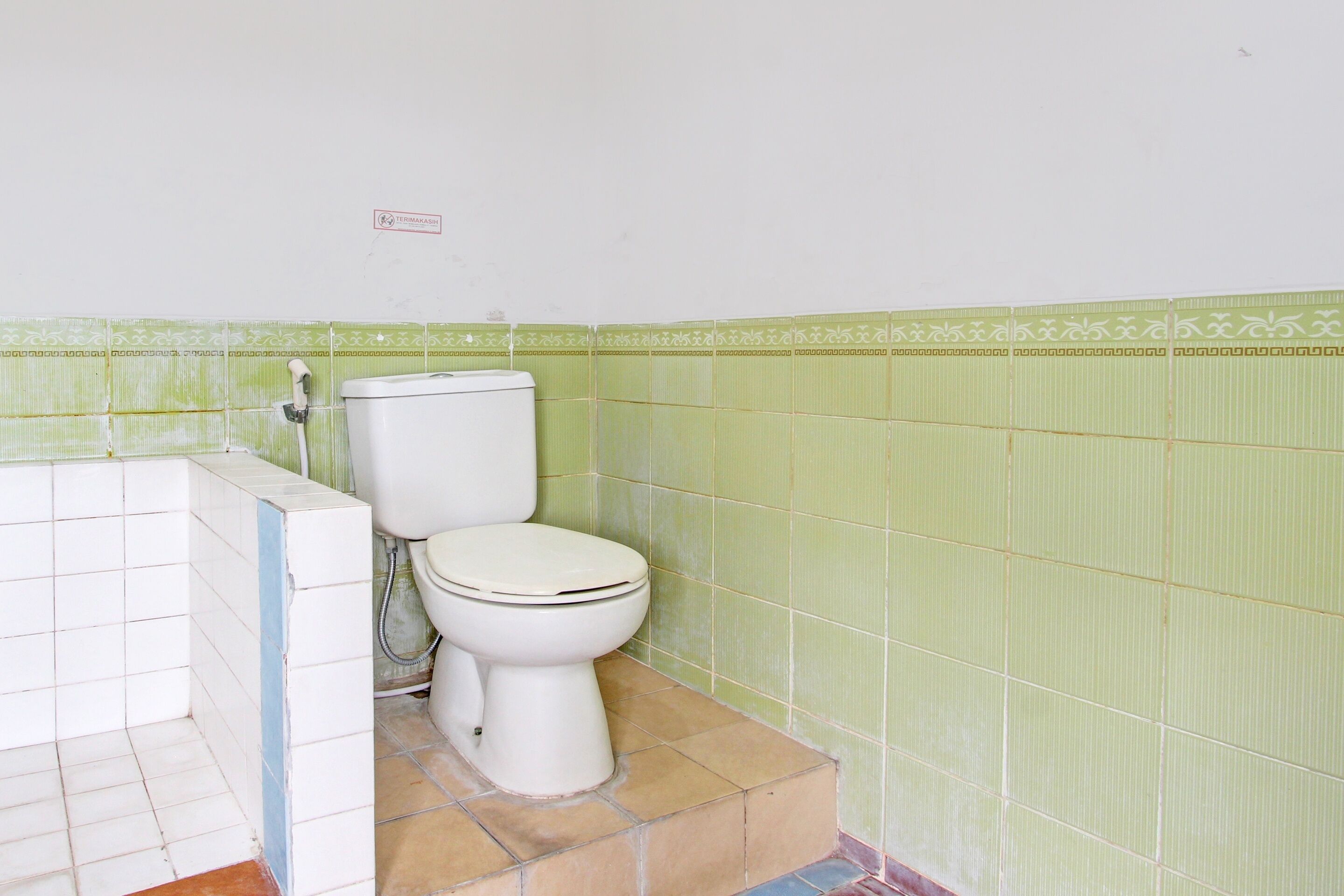 Ein Badezimmer mit Toilette, Dusche und Fliesenwand.