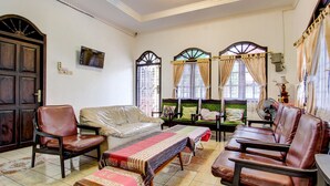 A traditional living room with a sofa, two armchairs, a wooden table, and a bench. - Hotel O Mw 46 Guesthouse (Yogyakarta)