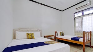 A room with two beds, a small table, and a window with curtains. - Hotel O Mw 46 Guesthouse (Yogyakarta)