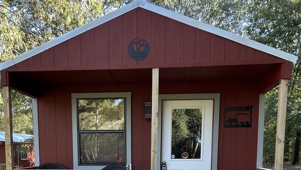 Une petite cabane avec une véranda, une porte et une fenêtre.