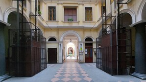 A corridor with a checkered floor, arched doorways, and a central archway leading to a bright interior. - Roman Holiday Suites (Rome)