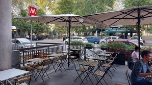 An outdoor café with tables and umbrellas, a gelato stand, and a McDonald's sign in the background. - Roman Holiday Suites (Rome)
