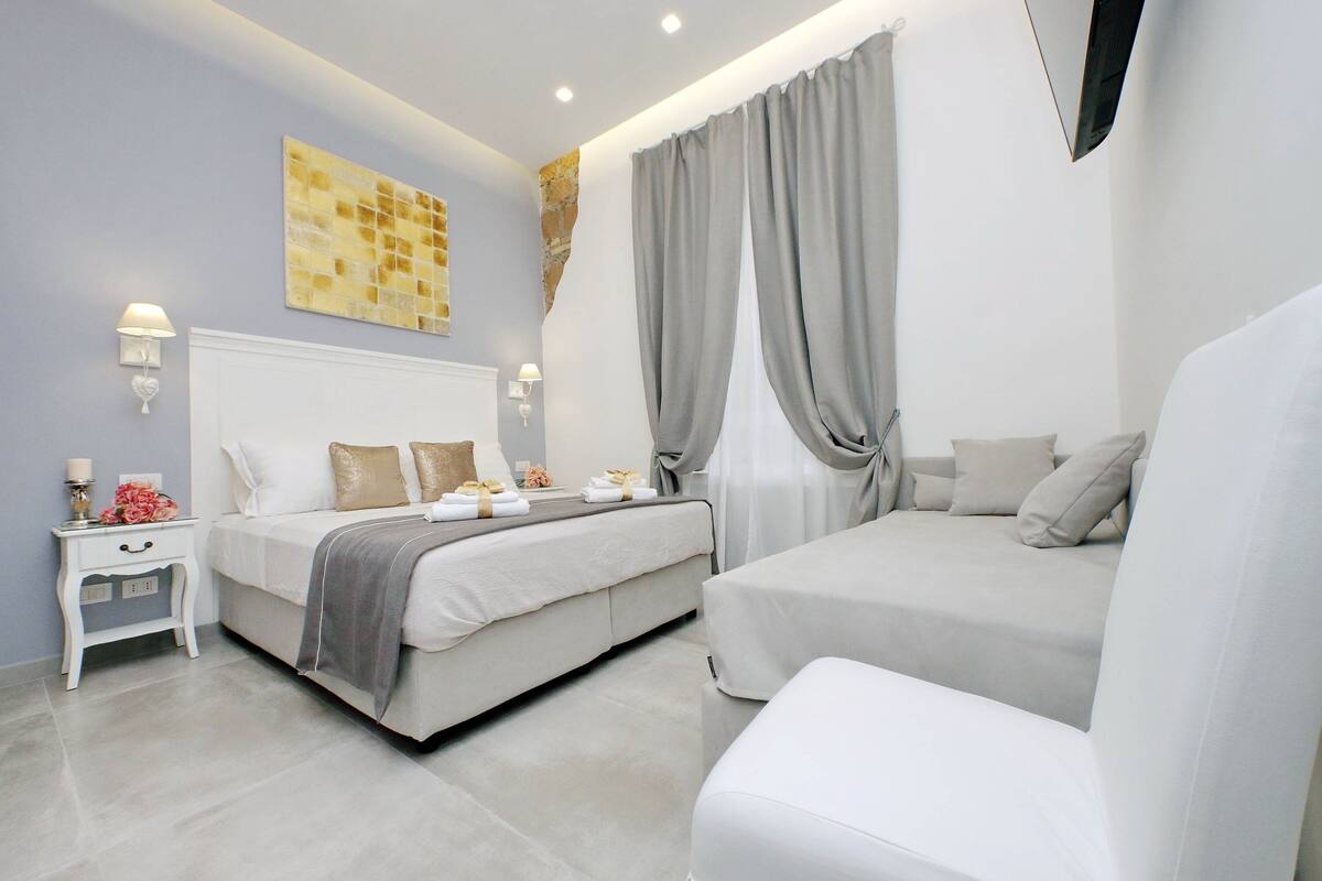 A modern bedroom with a bed, bedside tables, and a large window with curtains.
