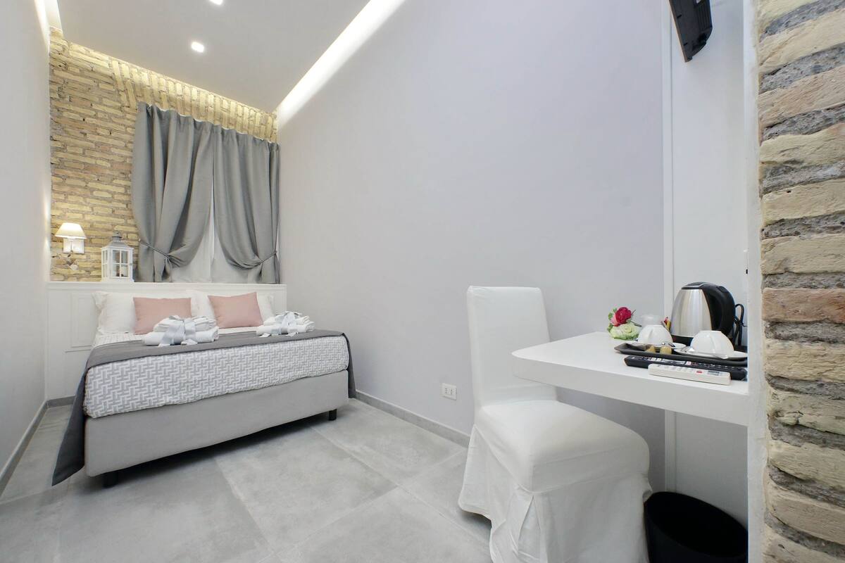 A modern bedroom with a bed, a white desk, and a brick accent wall.