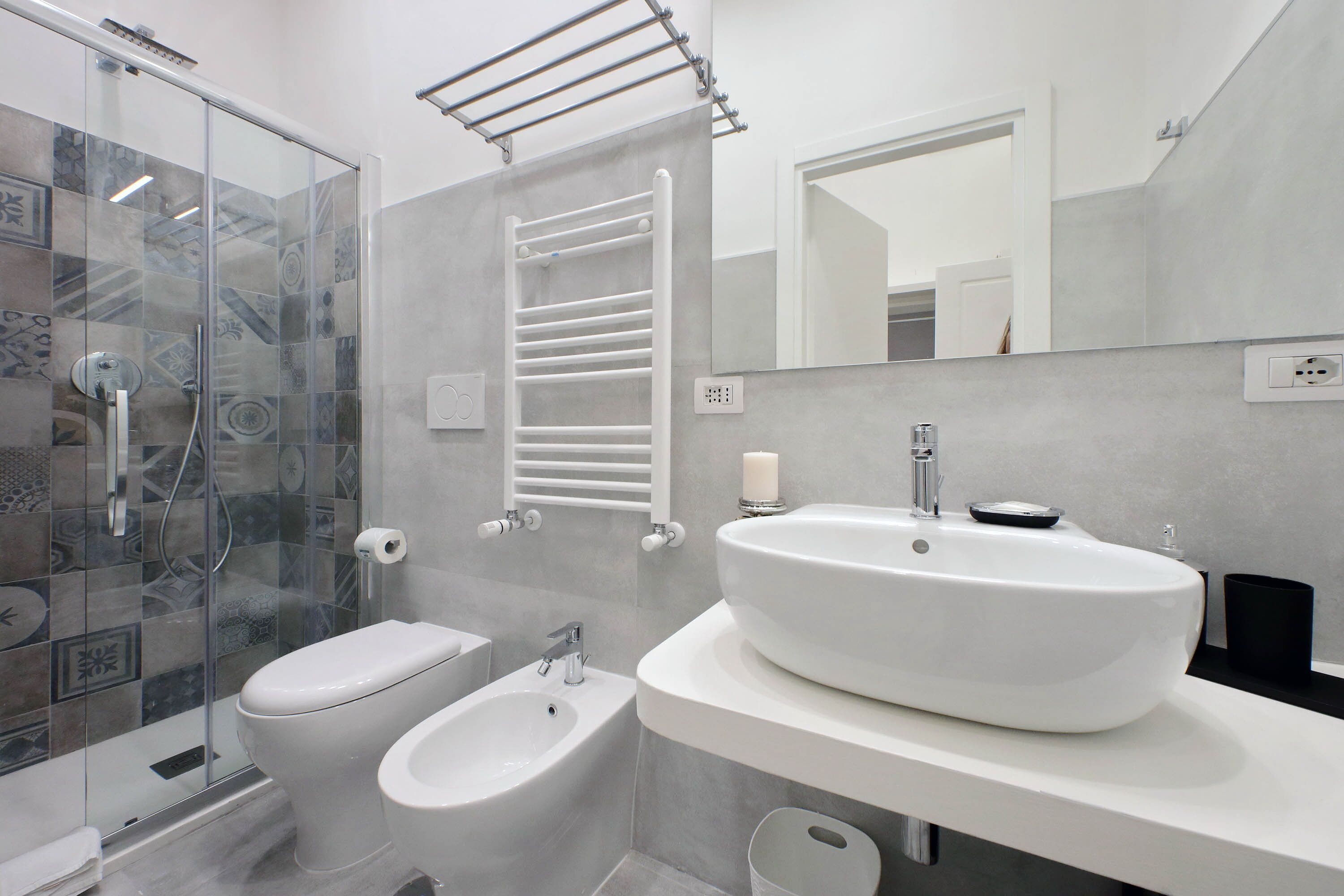 Ein modernes Badezimmer mit Duschkabine aus Glas, einem Bidet, einem großen Waschbecken und einem Handtuchhalter.