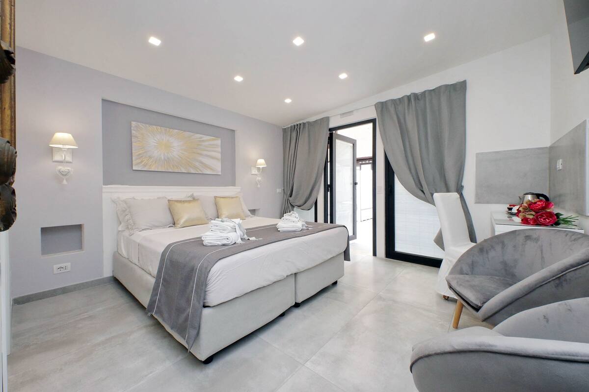 A modern bedroom with a bed, bedside tables, and a seating area.
