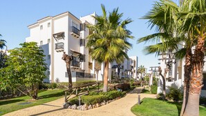 Un quartier résidentiel avec des bâtiments blancs, des palmiers et une promenade dallée.