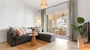 Un salon moderne avec un canapé gris, une table basse en bois et un meuble pour la télévision.