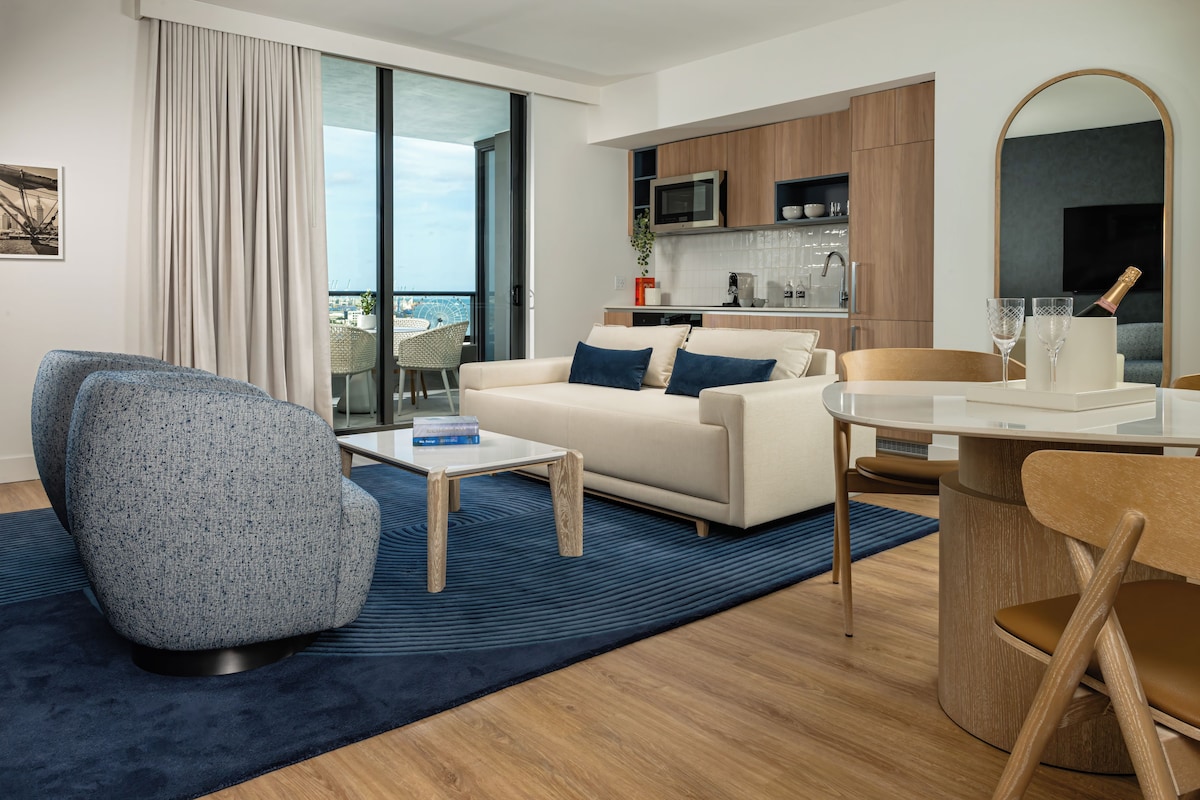 A modern living room with a sofa, a coffee table, and a dining area with a table and chairs.