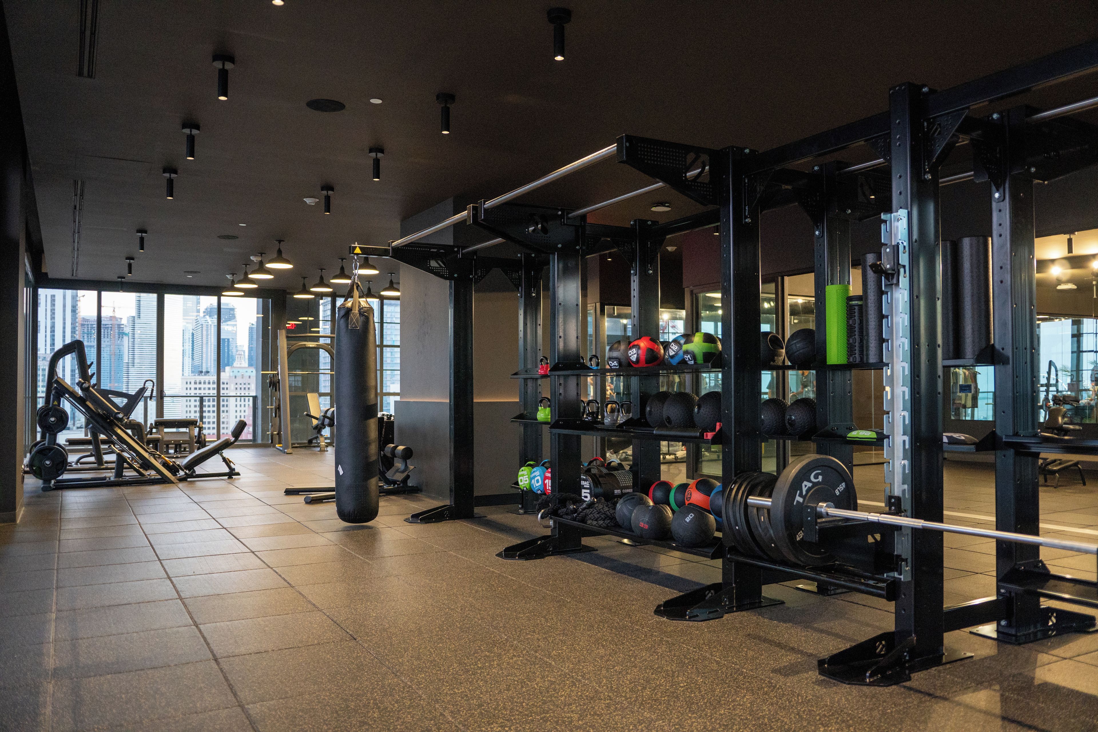 Un gimnasio con varios equipos de ejercicio, incluyendo mancuernas, kettlebells y una estructura para sentadillas.