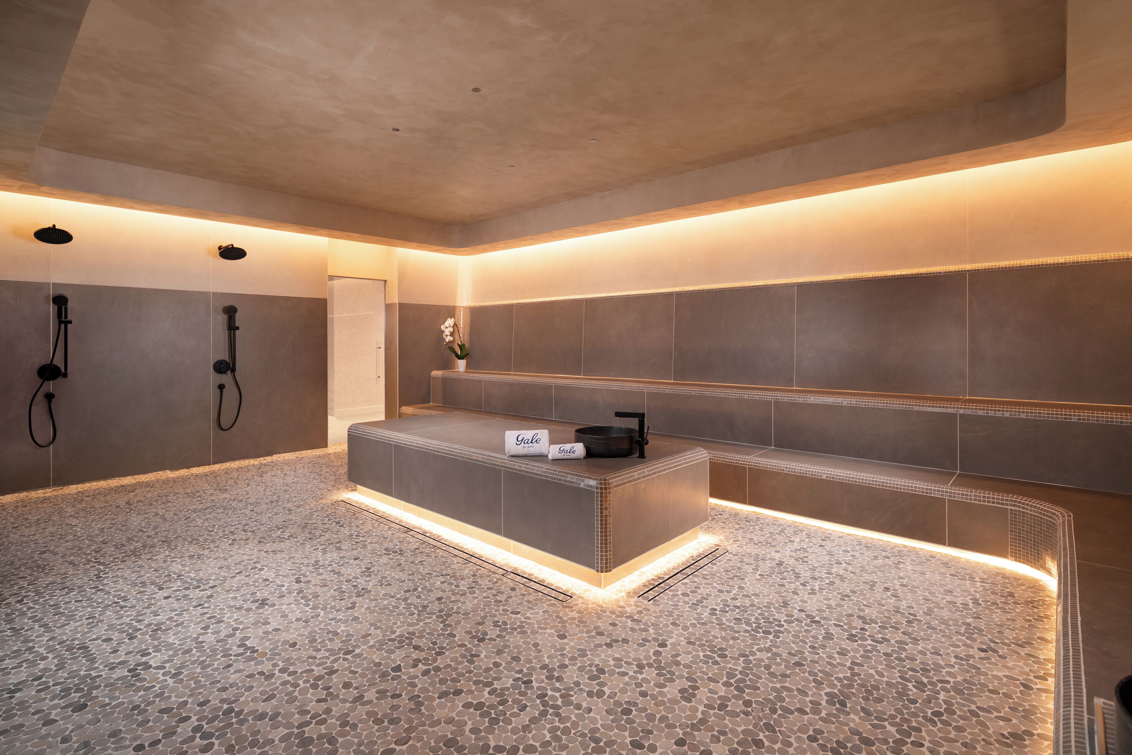 Un moderno espacio de spa con suelo de piedra, una recepción y dos cabezales de ducha.