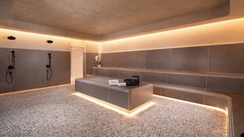 A modern spa area with a stone floor, a reception desk, and two showerheads.