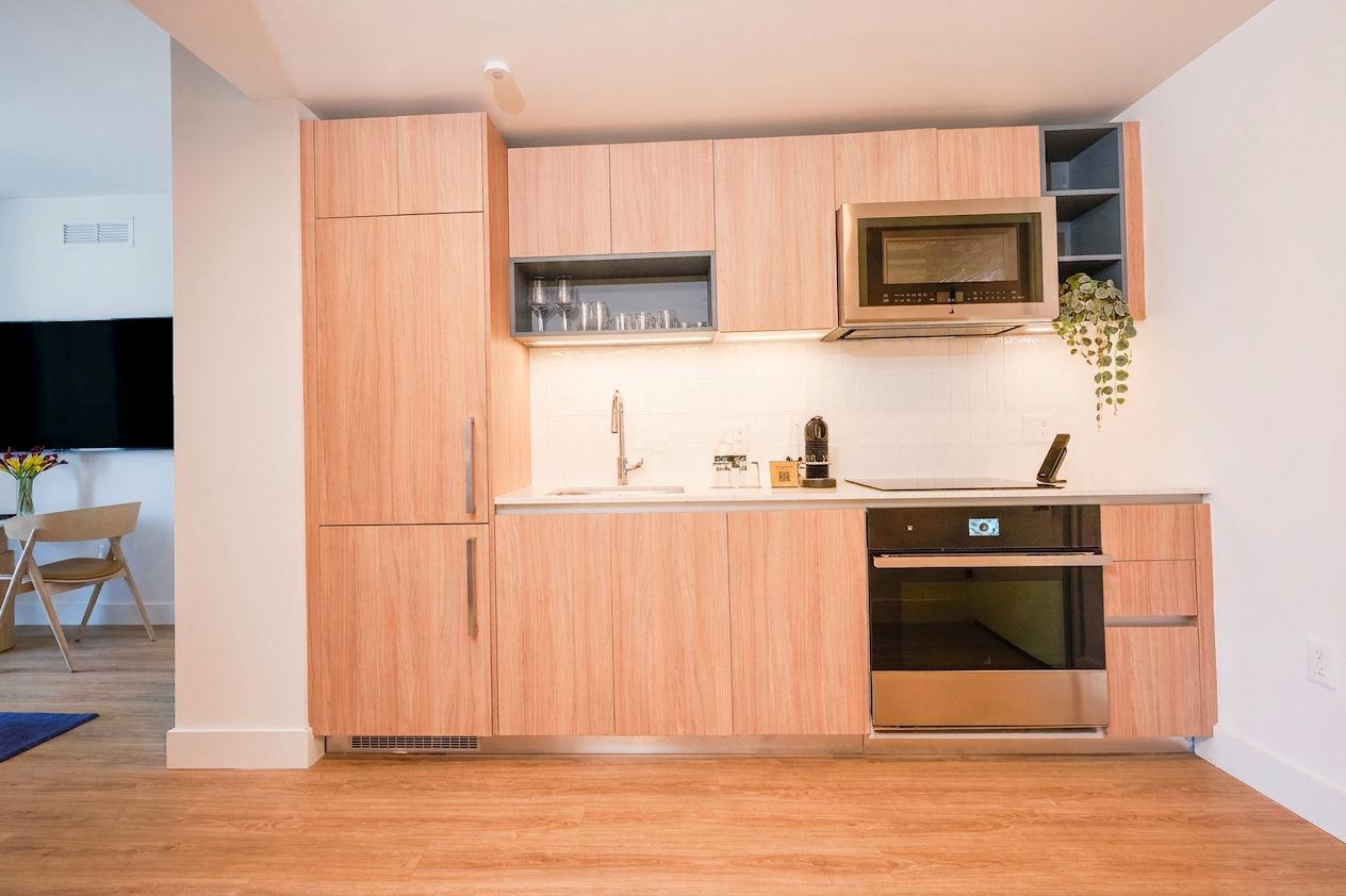 Een kleine keuken met houten kastjes, een magnetron en een inbouwoven.