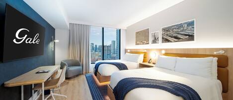 A hotel room with two beds, a desk, and a large window offering a city view.