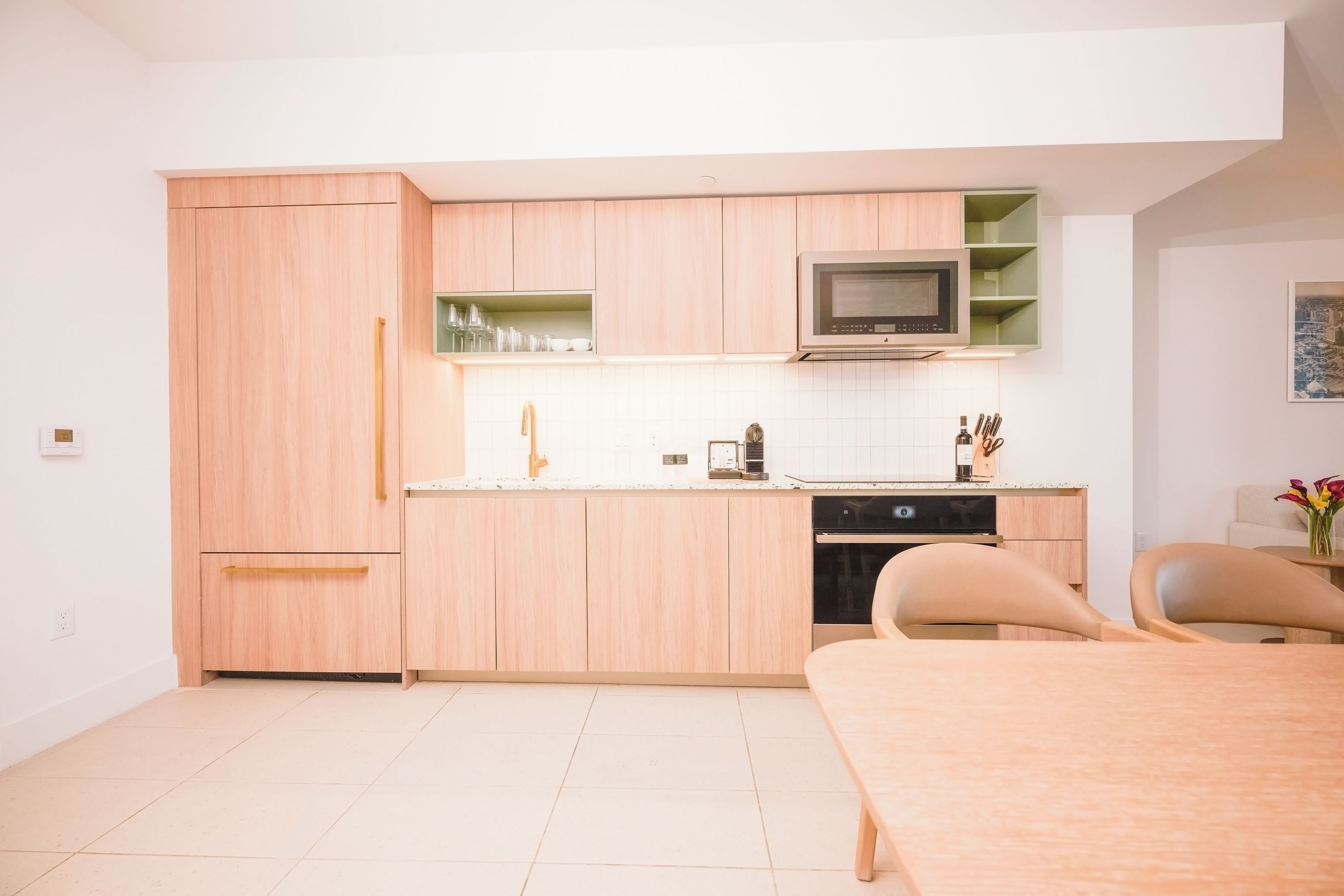 Una cocina moderna con armarios de madera, microondas y comedor con mesa y sillas.