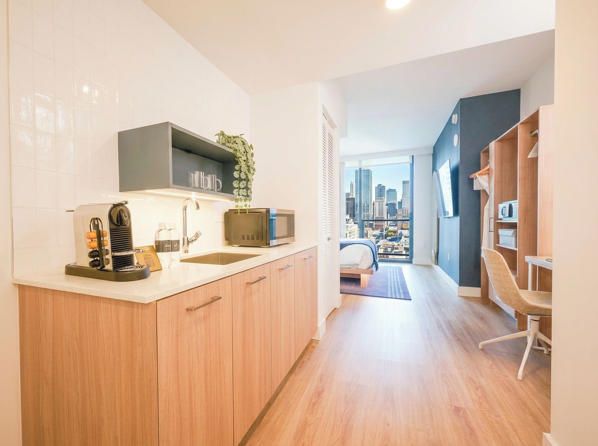 Una cucina moderna con vista sulla città, un'area pranzo con una sedia e un letto con vista sullo skyline.