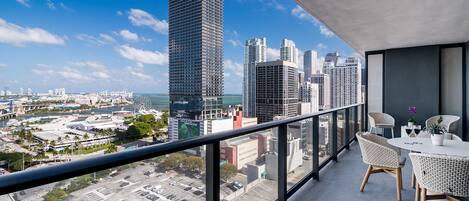 A balcony with a city view, a table with chairs, and a potted plant.