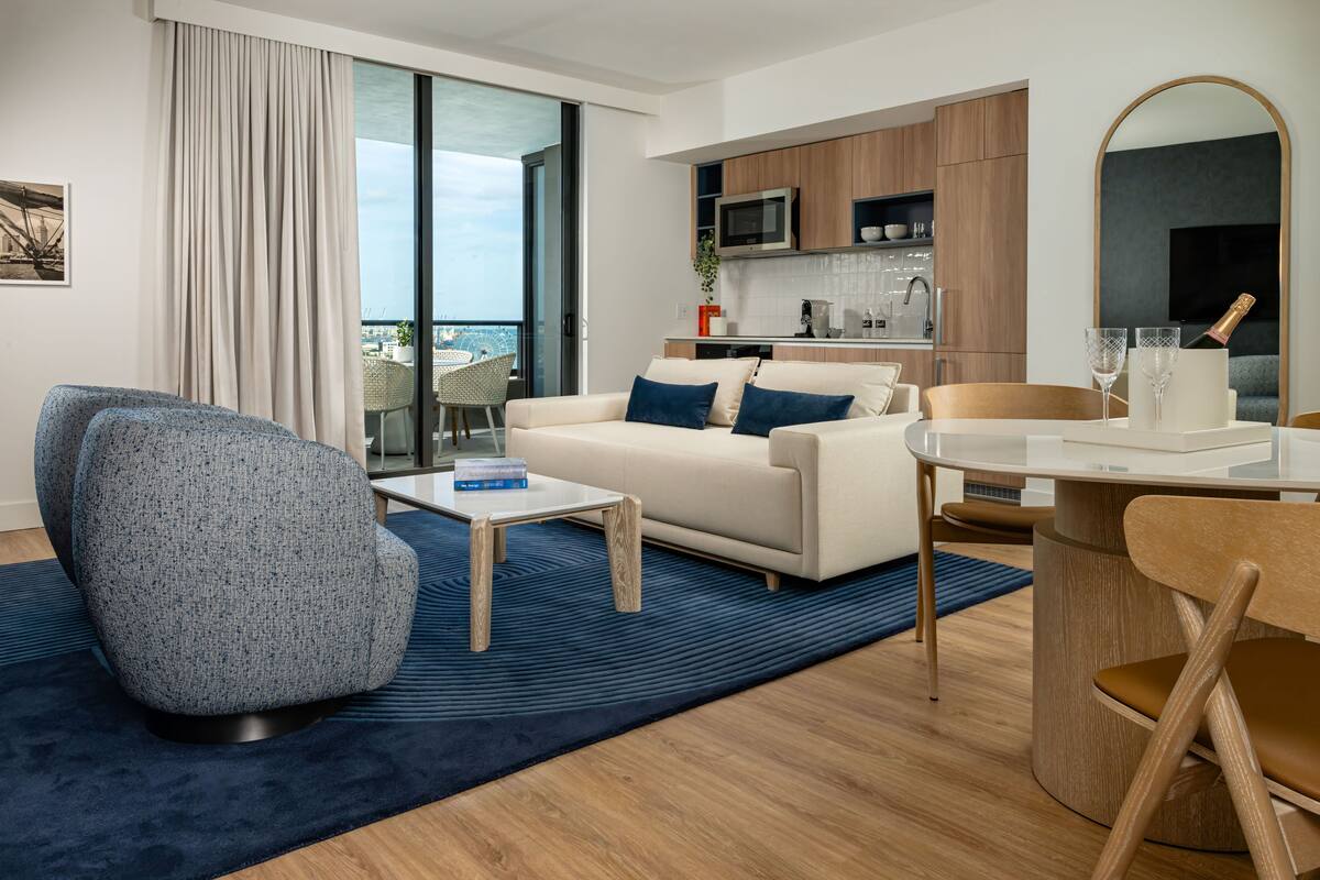A modern living room with a sofa, armchair, coffee table, and dining table.