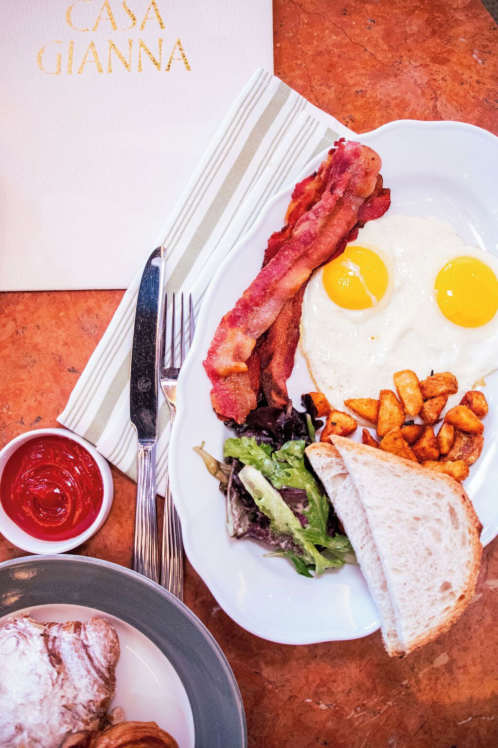 Un plato de desayuno con huevos, tocino, tostadas y ensalada.