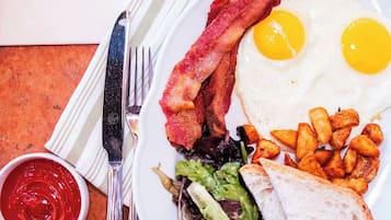 Un plato de desayuno con huevos, tocino, tostadas y ensalada.