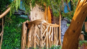 Una construcción rústica de madera en un entorno natural que recuerda a un bosque.