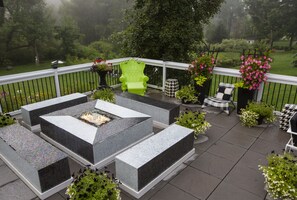 A patio with a fire pit, outdoor furniture, and potted plants.