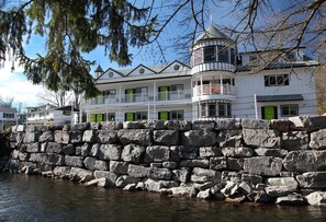 A waterfront property with a stone wall, a turret, and multiple green doors.