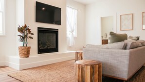 A modern living room with a fireplace, a sofa, a TV, and a potted plant. - Luxury Village Home Close to Beaches and Wineries! (Arroyo Grande)