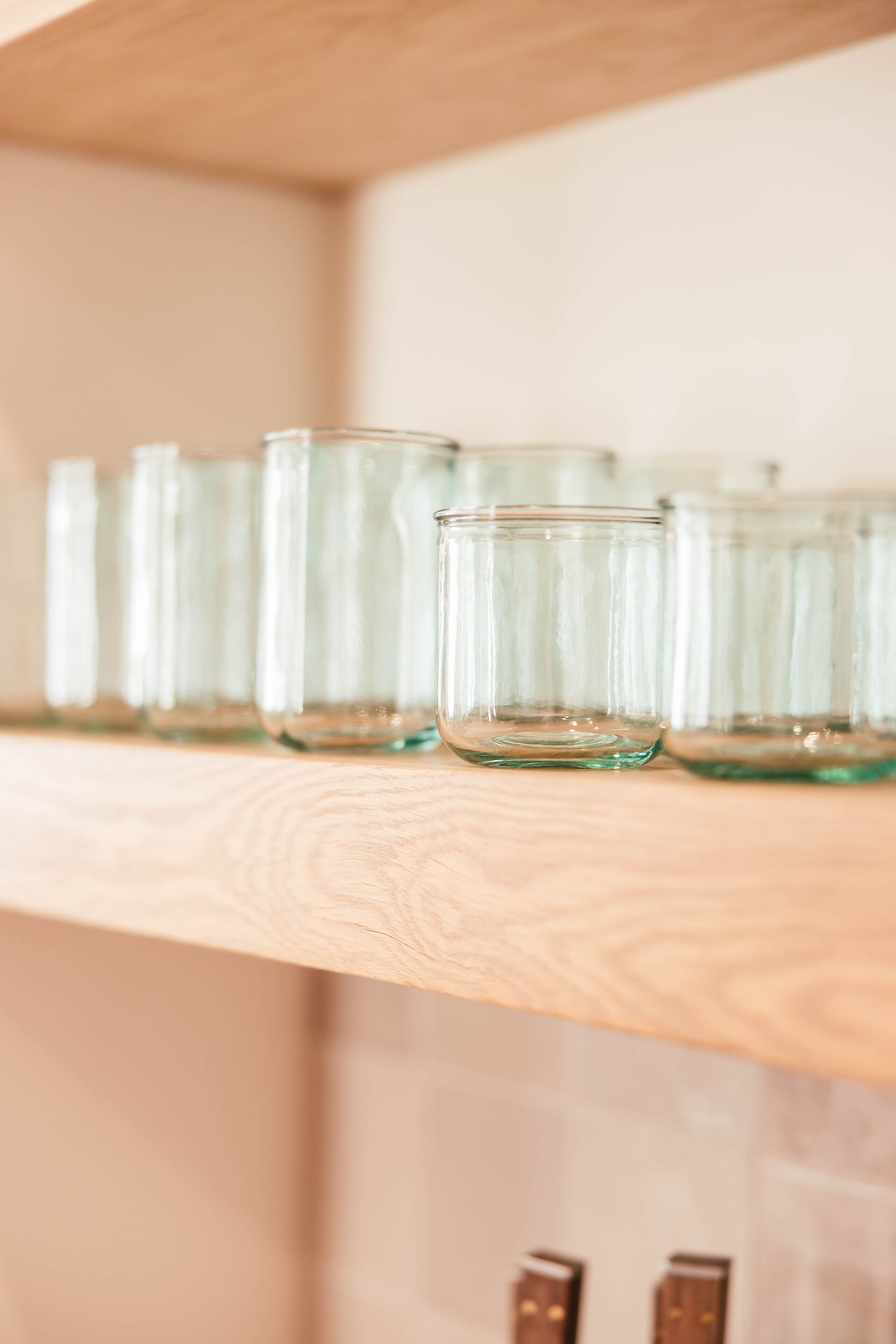 A wooden shelf with several clear glass jars.