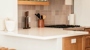 A kitchen with a white countertop, wooden stools, and a backsplash of gray tiles. - Luxury Village Home Close to Beaches and Wineries! (Arroyo Grande)