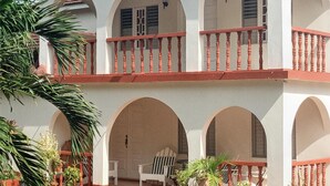 Un edificio de dos pisos con fachada blanca, barandillas de balcón rojas y varios arcos.