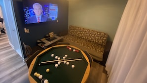 A room with a pool table, a television, and a patterned sofa. - Pristine 3bed , 3bath 1 min walkto the beach water amusement park. Hot Tub 5 TVs (Keansburg)
