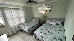 A hotel room with two beds, a ceiling fan, a decorative wall piece, and a window with curtains. - Pristine 3bed , 3bath 1 min walkto the beach water amusement park. Hot Tub 5 TVs (Keansburg)
