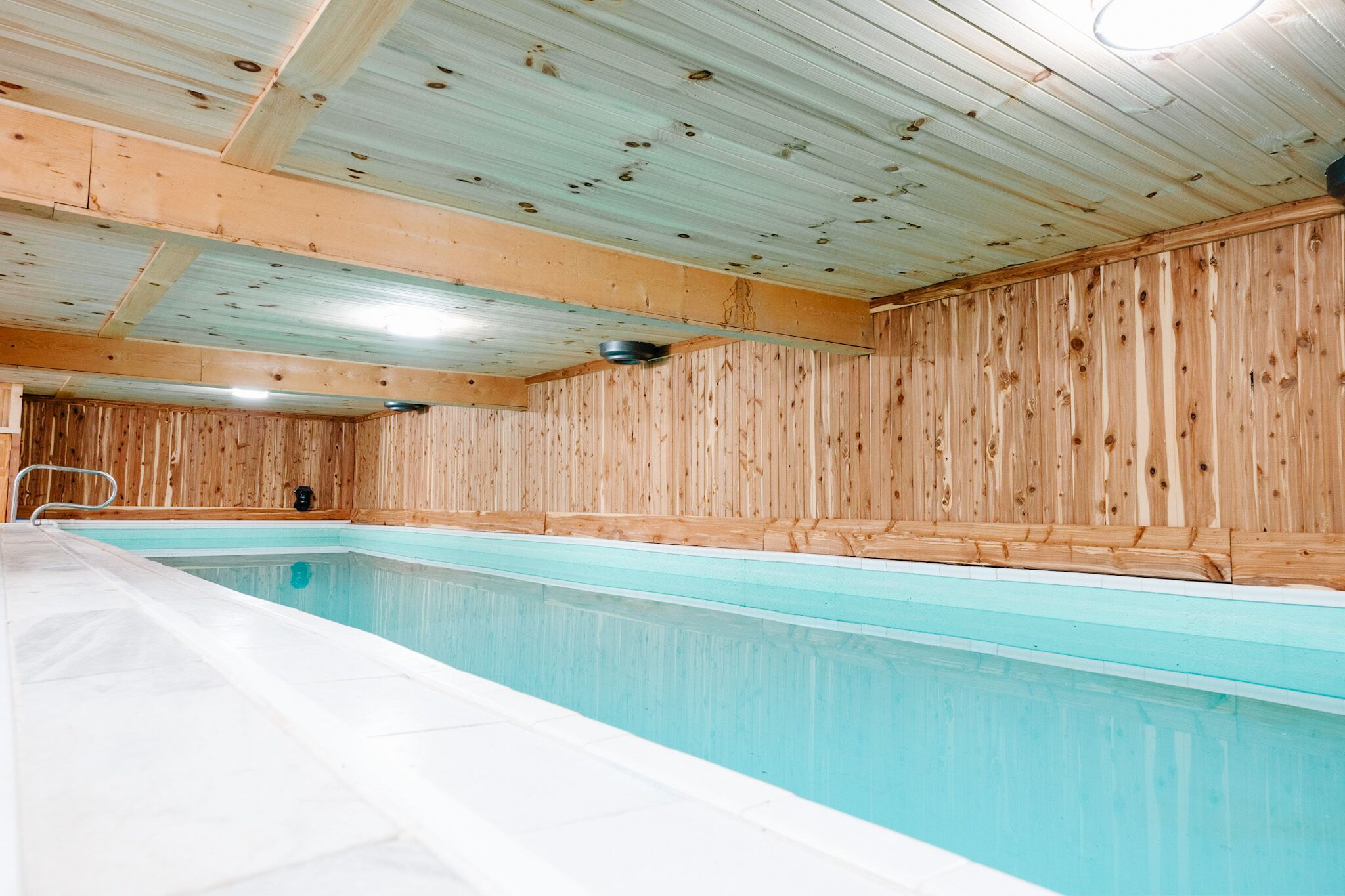 An indoor swimming pool with wooden walls and a tiled floor.