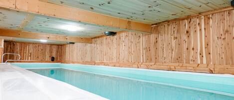 An indoor swimming pool with wooden walls and a tiled floor.