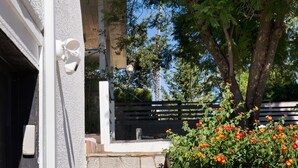 A set of stone steps leading up to a door, a white wall, and a flower bed with red flowers. - Safari Vines Retreat. Fully remodeled spacious 3 bedroom 2 bath home   
Sleeps 8 (Escondido)