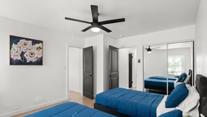 A modern bedroom with two beds, a ceiling fan, and a large mirror. - Safari Vines Retreat. Fully remodeled spacious 3 bedroom 2 bath home   
Sleeps 8 (Escondido)